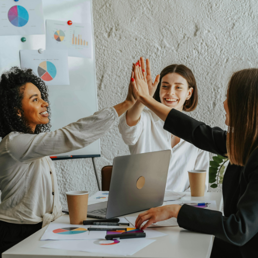 Image of workers around a table high-fiving eachother